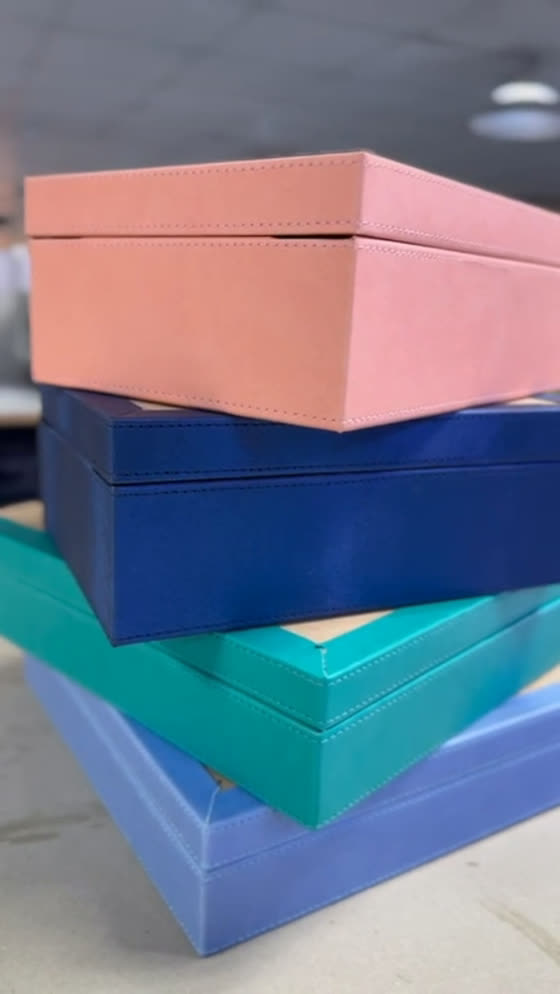 Finished stitched leather boxes stacked in salmon, navy, teal and periwinkle